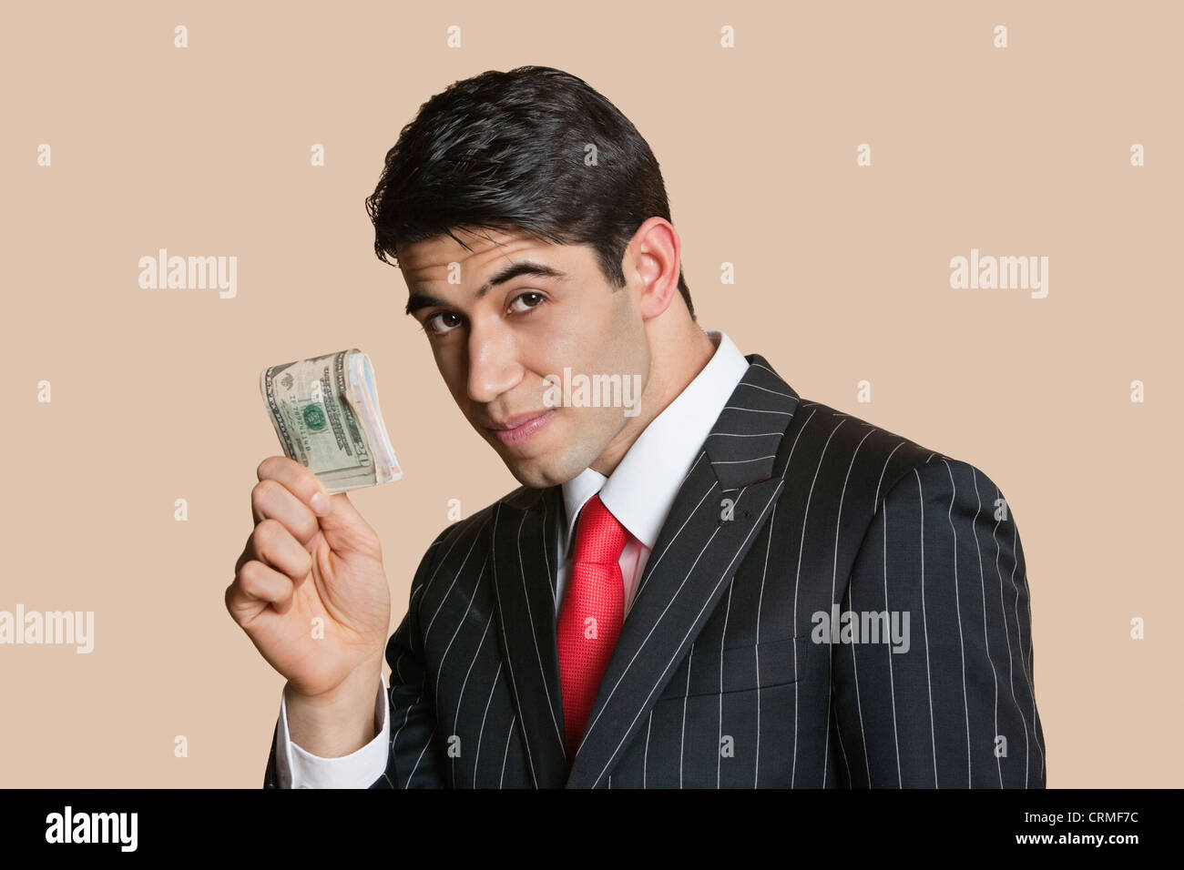 Portrait of a young businessman showing paper money over colored background Stock Photo