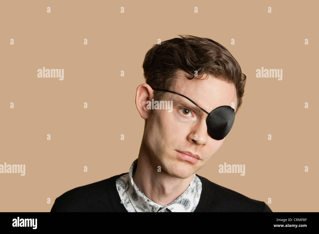 Sad mid adult man wearing eye patch over colored background Stock Photo