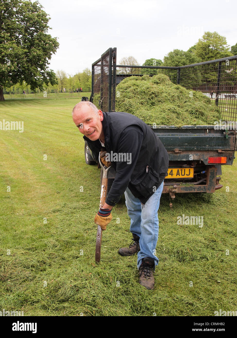 Gardener raking grass clippings at Kensington Palace, London, England