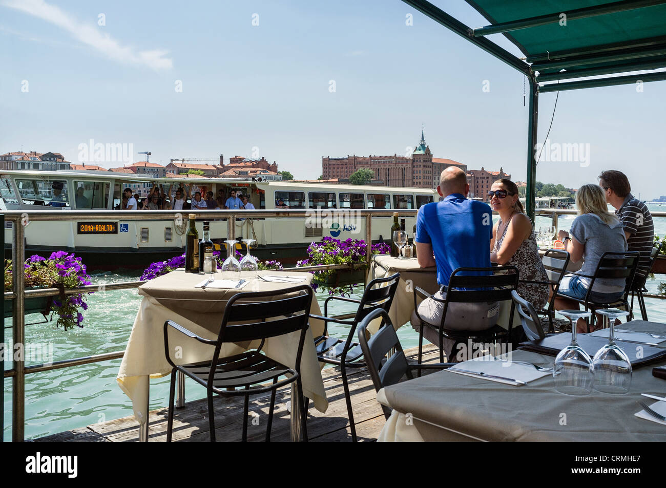 A valporetto passing diners eating out at a canal side restaurant in Dorsoduro Venice. Stock Photo