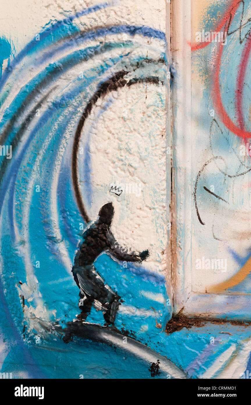 Vertical section of a wall in an alley in downtown Aberdeen, Washington with a surfer and wave spray painted on the wall. Stock Photo