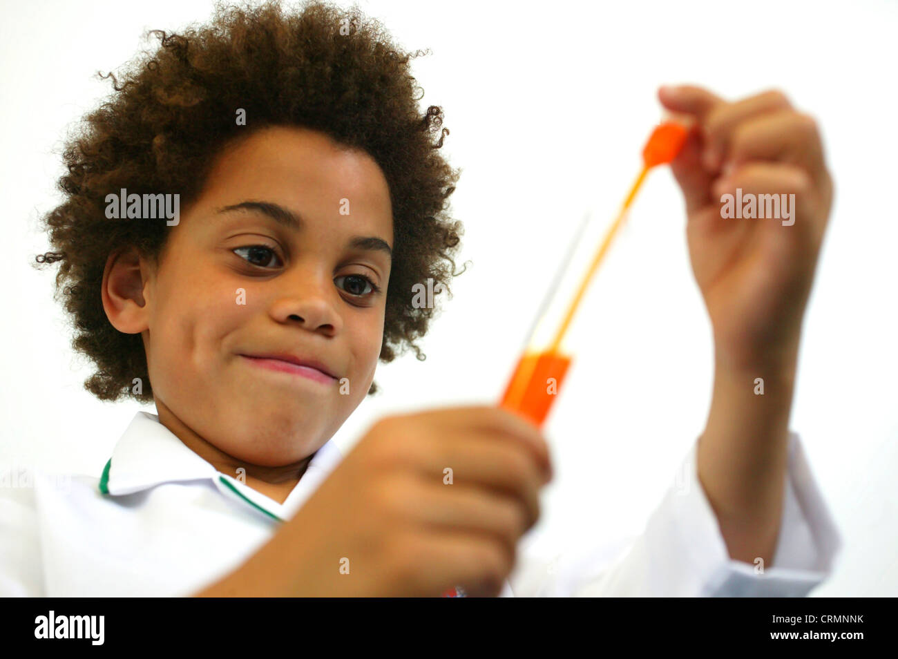 A Young African Boy Dressed As A Pharmacist Examines A Test Tube Of Orange Liquid A Young African Boy Dressed As A Pharmacist Examines A Test Tube Of Orange Liquid