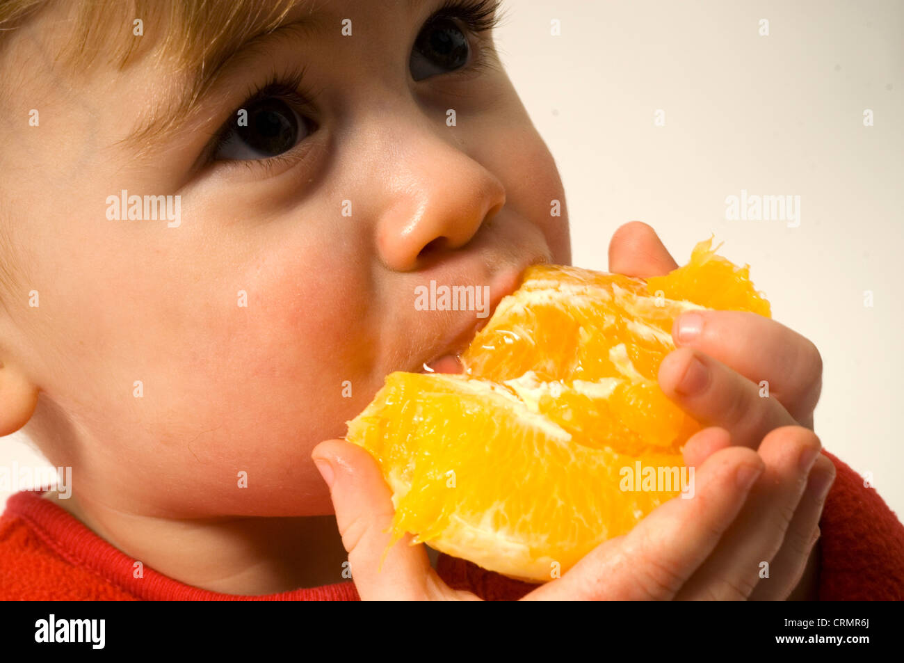 Young boy eating an orange Stock Photo Alamy