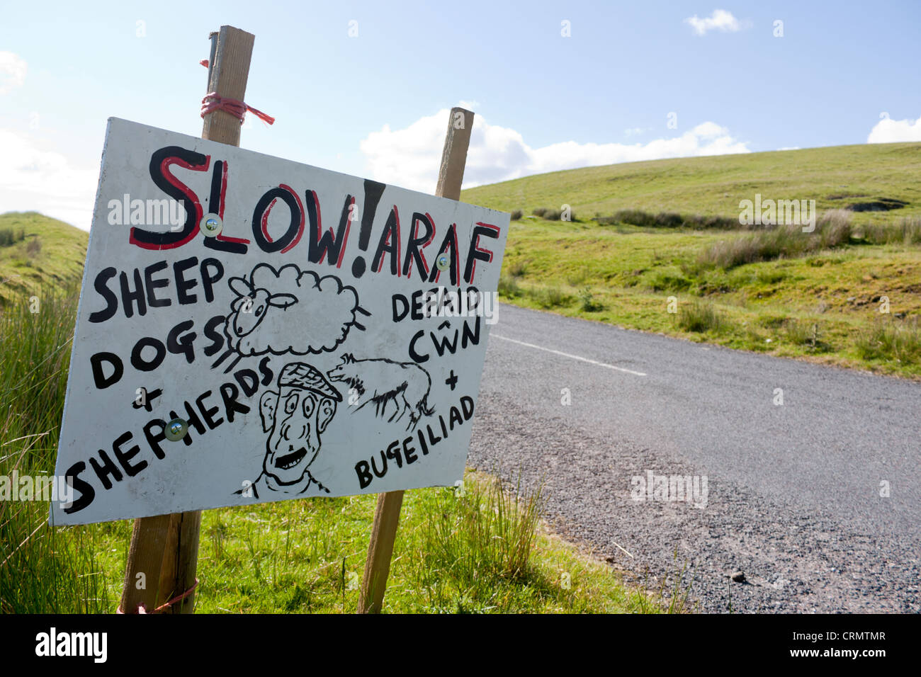 Slow Araf humorous handpainted sign by side of Welsh mountain road warning to beware of sheep, dogs and shepherds Powys Wales UK Stock Photo