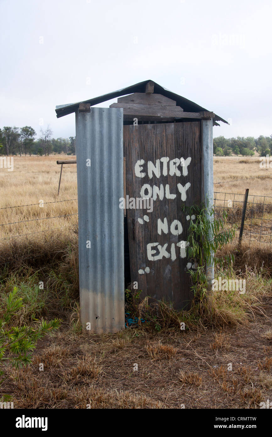 Aussie toilet humour 'Entry Only No Exit' sign painted on door of ramshackle outdoor drop toilet Begonia Queensland Australia Stock Photo