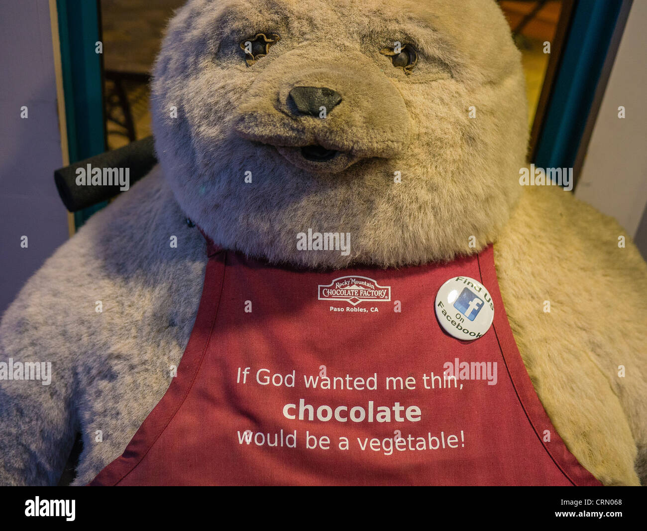 A large children's stuffed bear wears an apron with a very funny sentence on it outside a chocolate store, Paso Robles, CA. Stock Photo