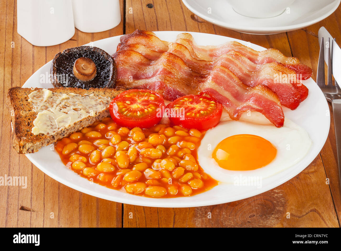 Full English breakfast on an old pine kitchen table. Stock Photo