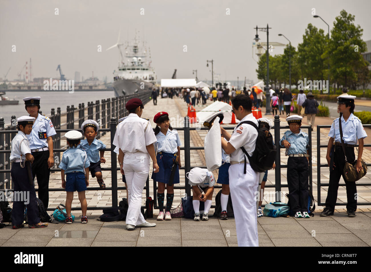 Children in sailor outfits lounge at Yokohama waterfront. Stock Photo