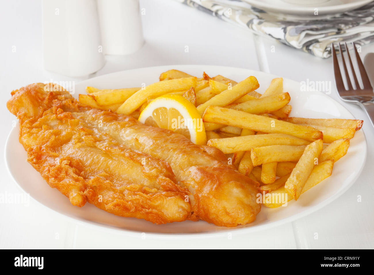Battered fish with chips in a light, bright setting. Stock Photo