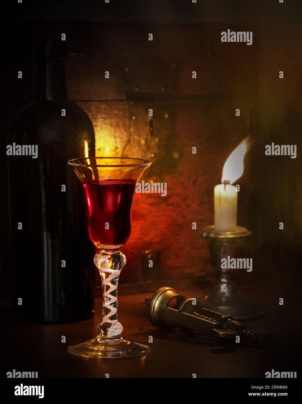 Candle lit scene with vintage port in antique glass Stock Photo