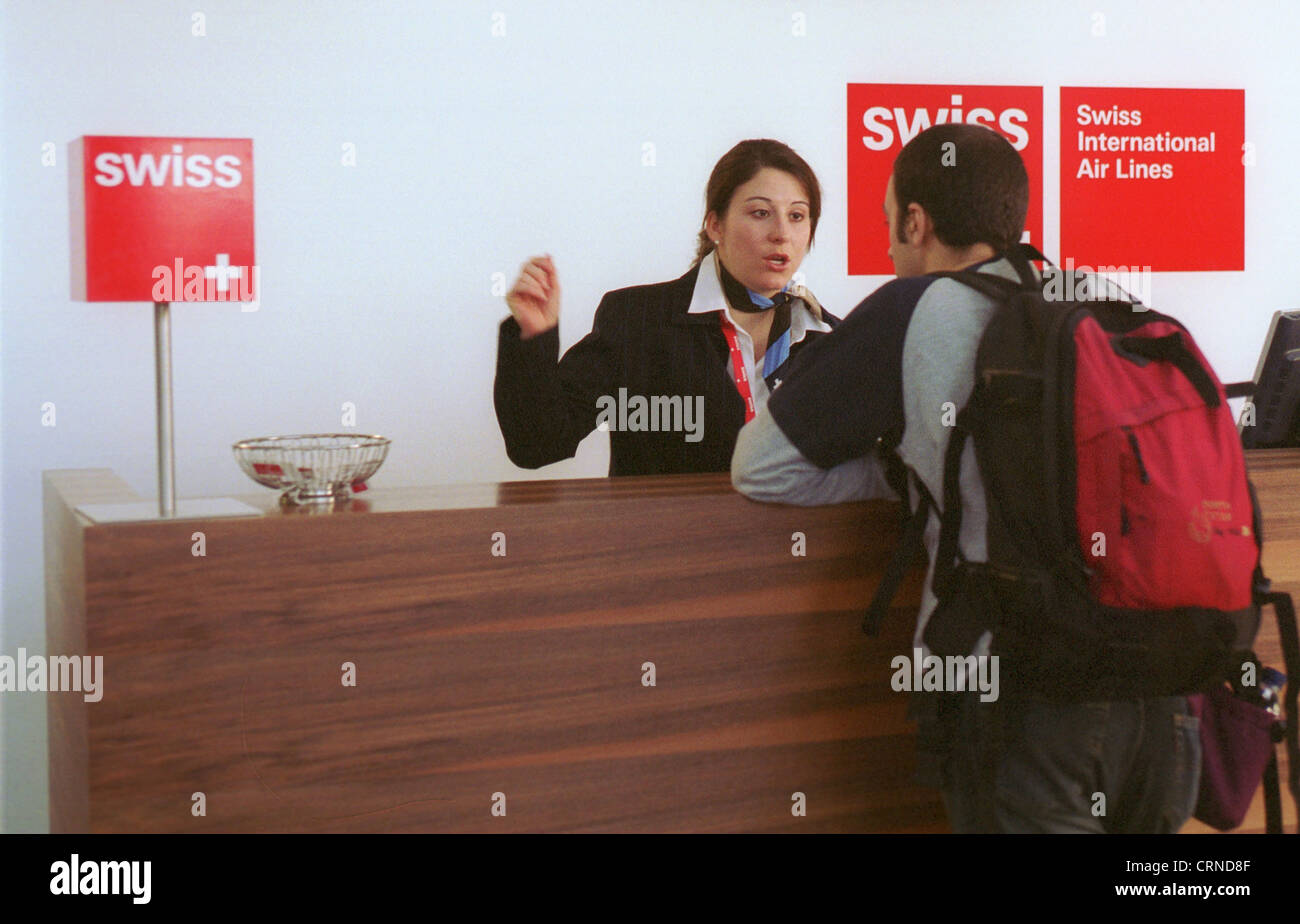 An employee of Swiss in conversation with a passenger at check-in Stock Photo