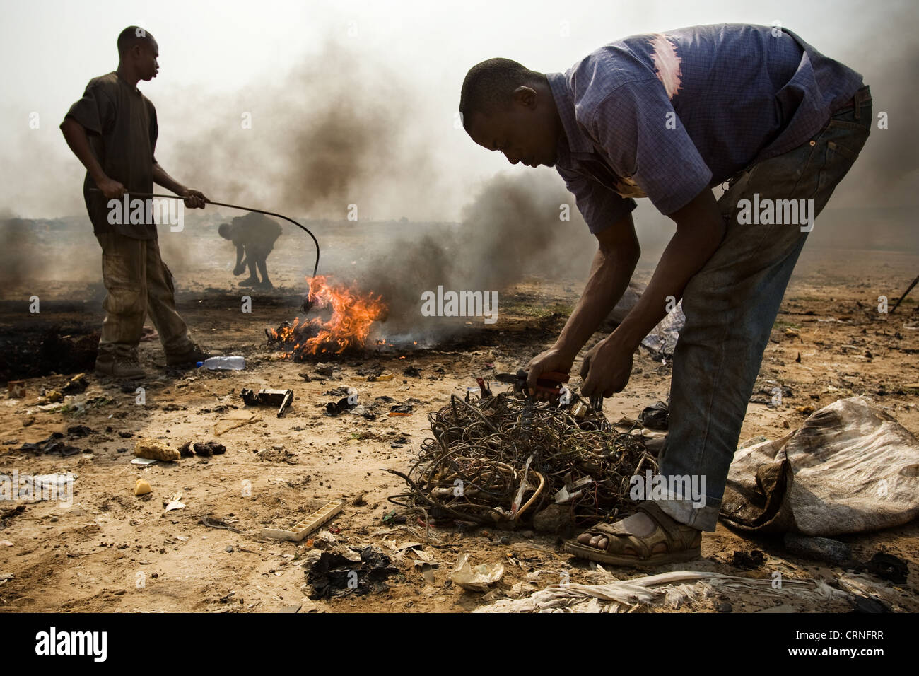 Teenage boys burn cables from computers and other electronics to recover copper near the Agbogboloshie slum in Accra, Ghana Stock Photo