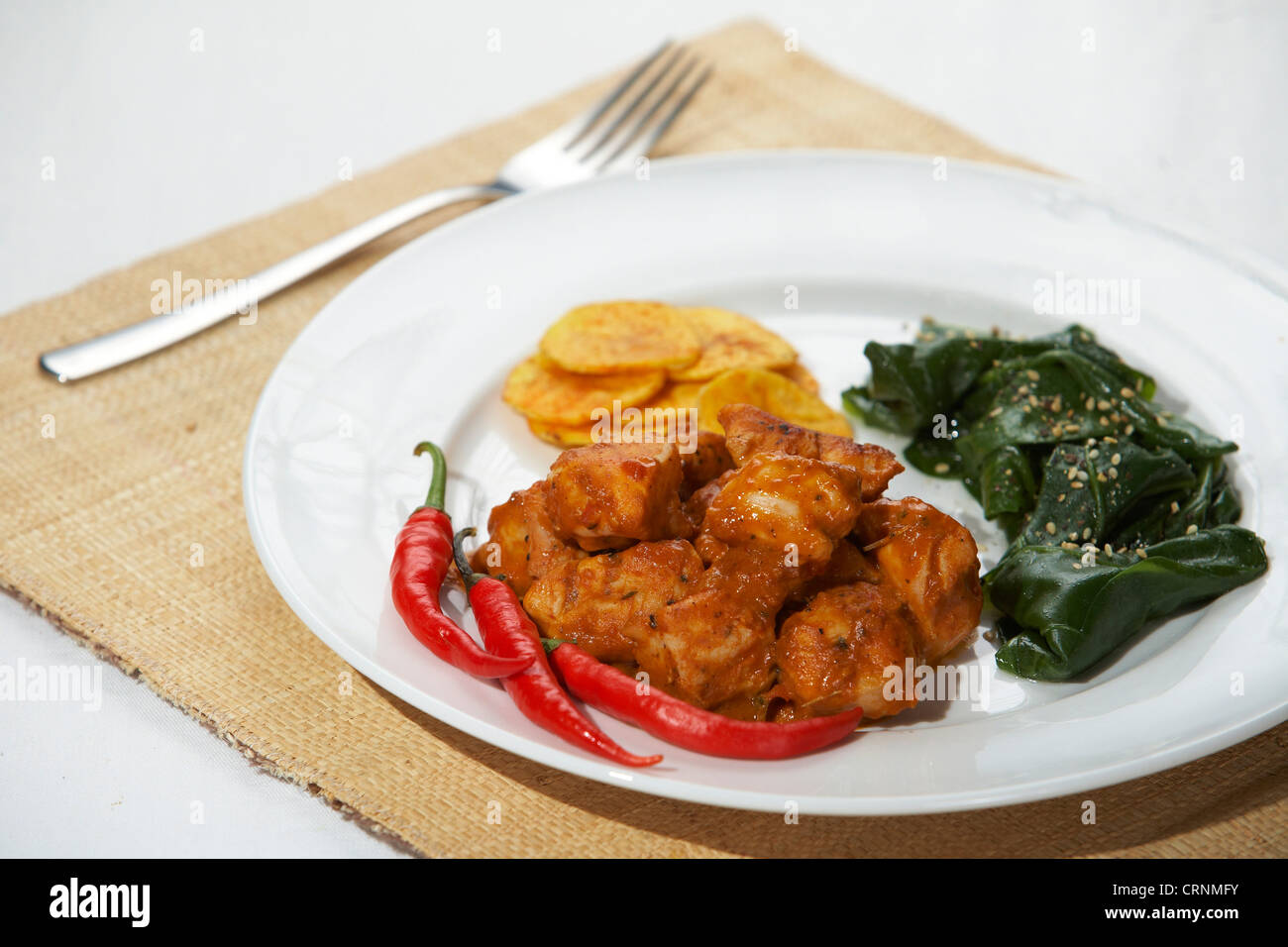 Spicy chicken with spinach and plantain chips. Stock Photo