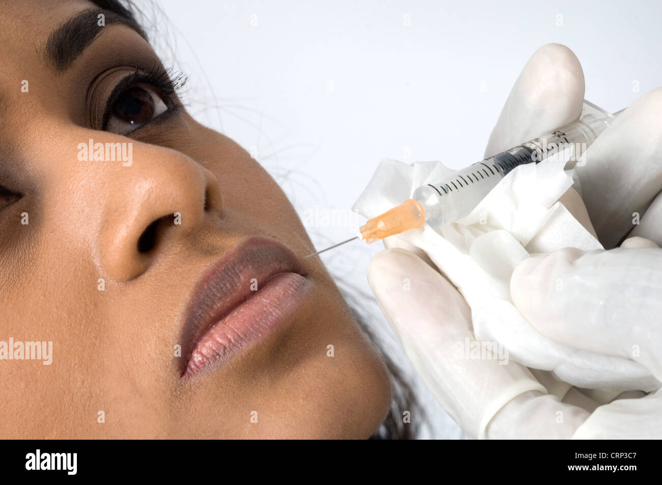 A surgeon injecting collagen into a woman's upper lip. Stock Photo