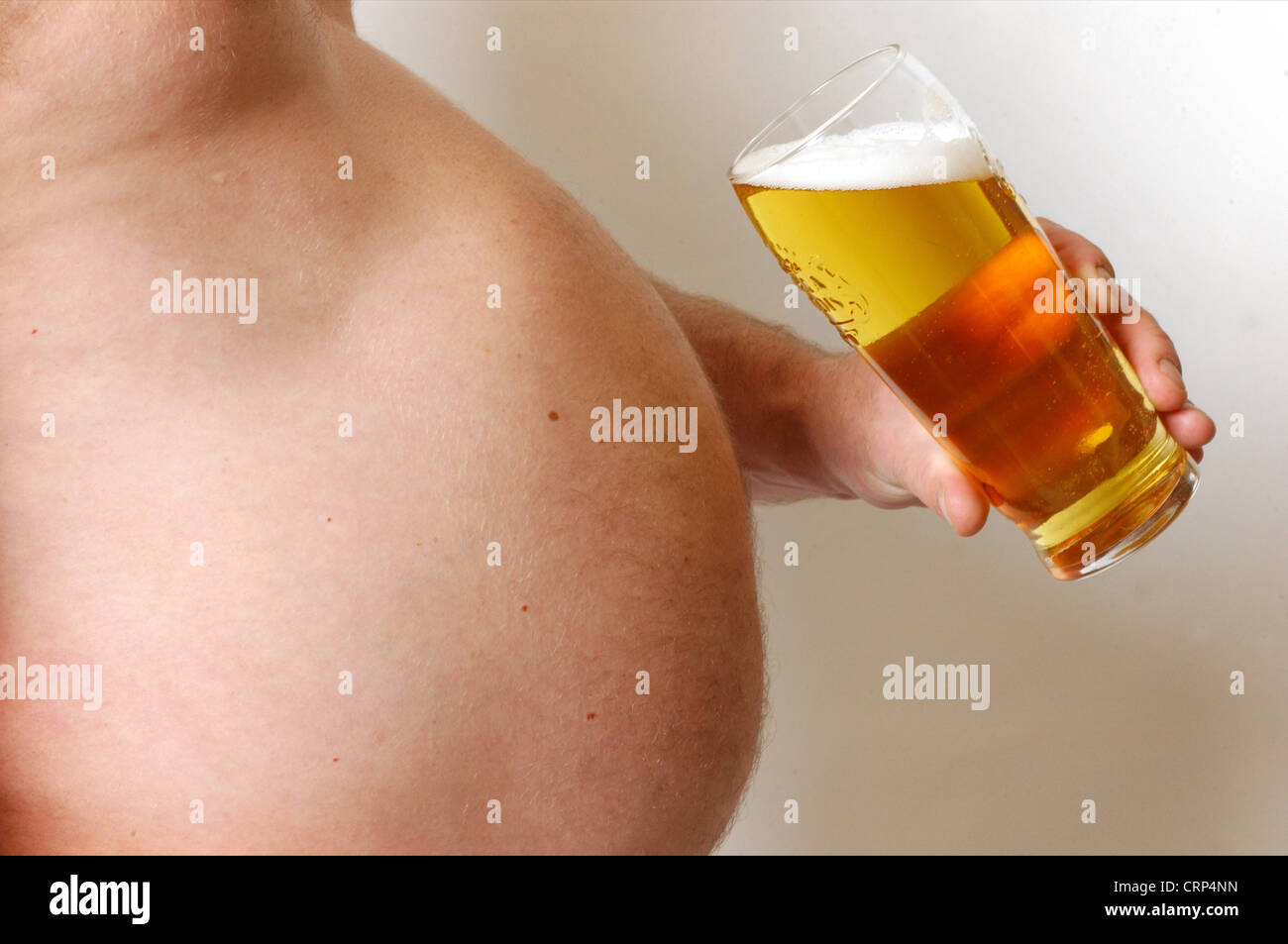 Man with a large beer gut holding a pint glass full of beer. Stock Photo