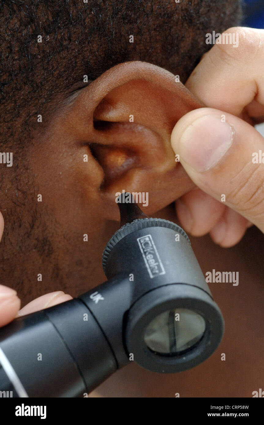 A GP uses an otoscope to examine a young man's ear Stock Photo Alamy