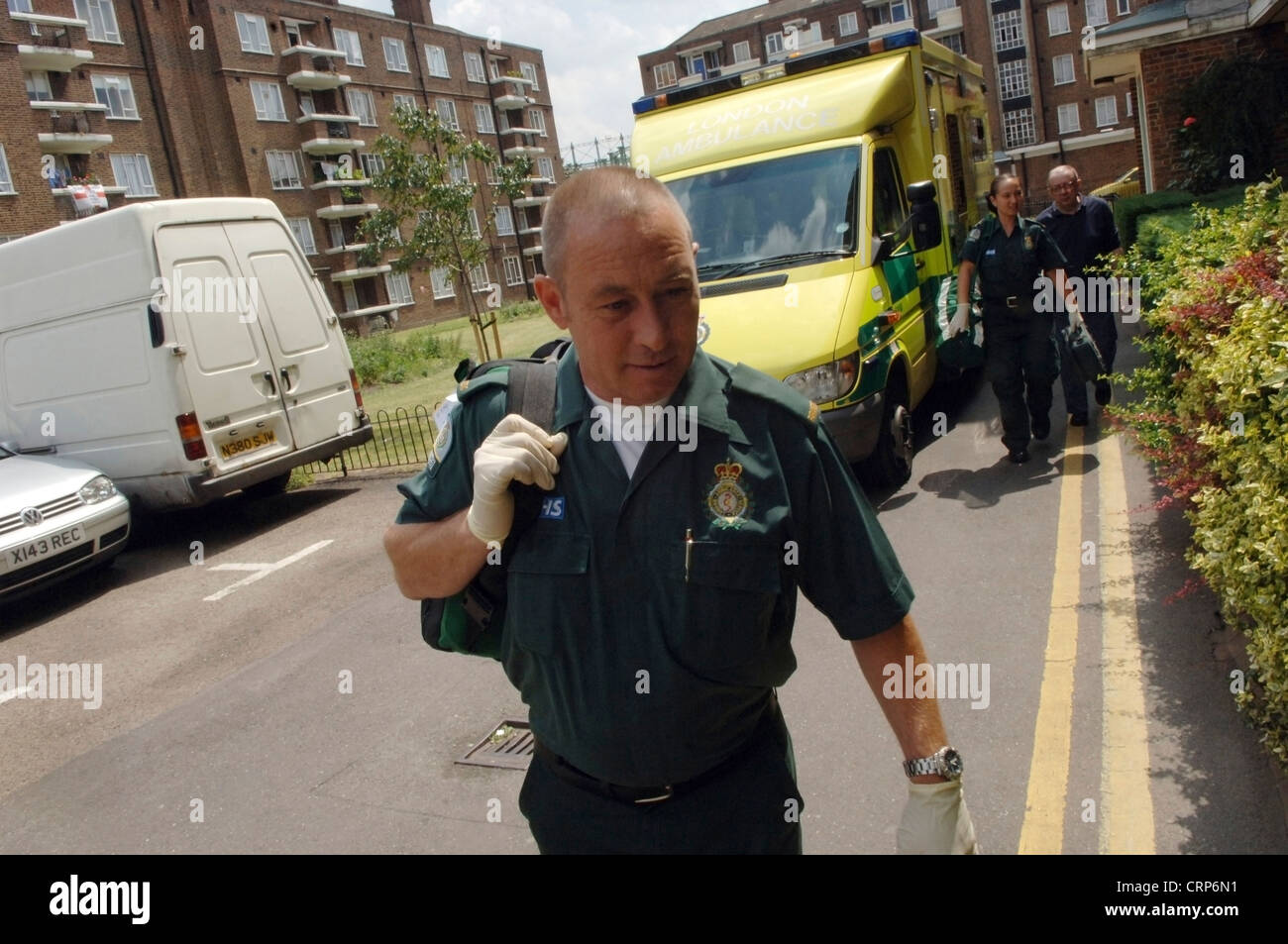 A male NHS London Ambulance Service paramedic with crew and yellow ambulance in the background Stock Photo
