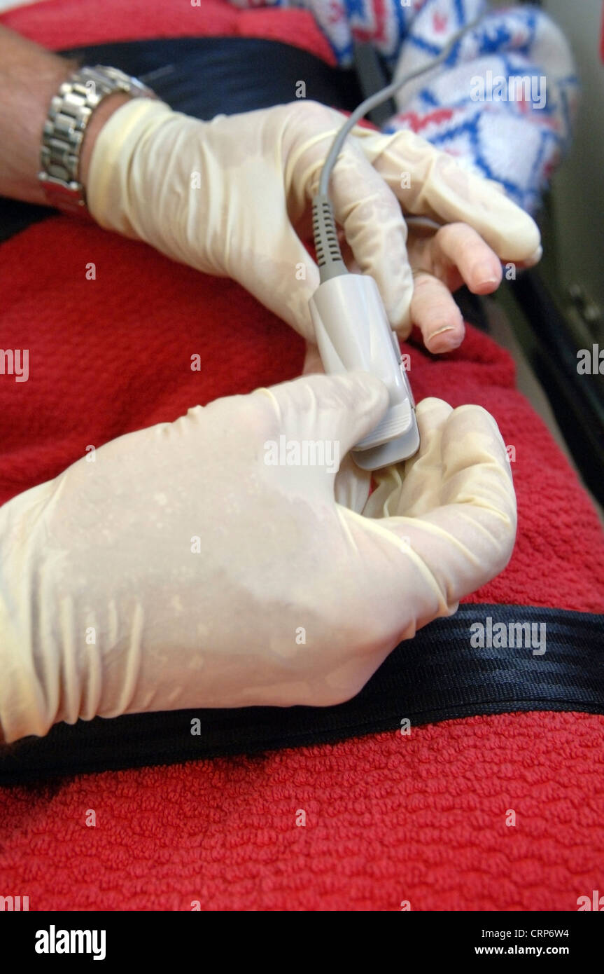 A paramedic using an oximeter to measure a patient's pulse rate and the oxygen concentration of the blood. Stock Photo