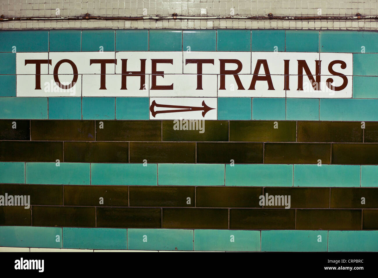 'To the trains' sign on a tiled wall in an underground station, London, England, UK. Stock Photo