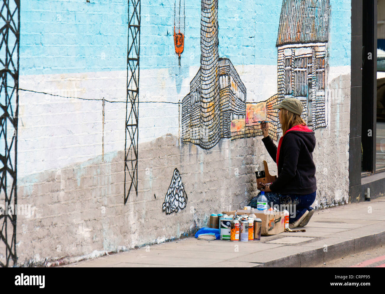 Street artist painting on a wall in Shoreditch in the east end of London. Stock Photo
