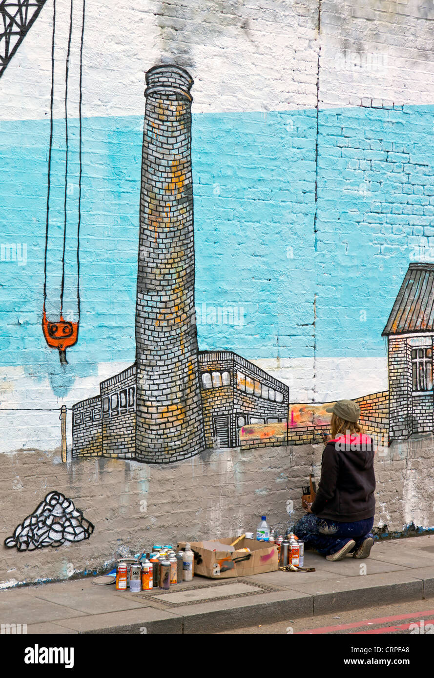 Street artist painting on a wall in Shoreditch in the east end of London. Stock Photo