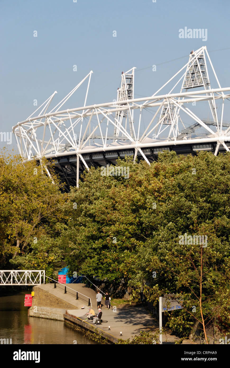 People walking along the riverside on the Lea Valley Walk with the Olympic Stadium in the background. Stock Photo