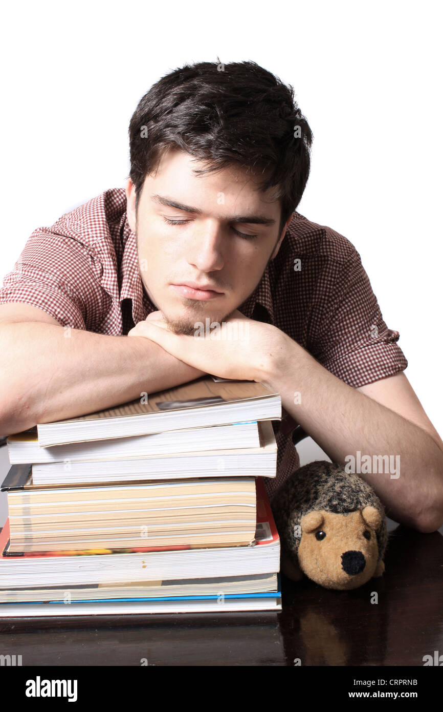 Eighteen year old male sleeping on school textbooks while sitting at a