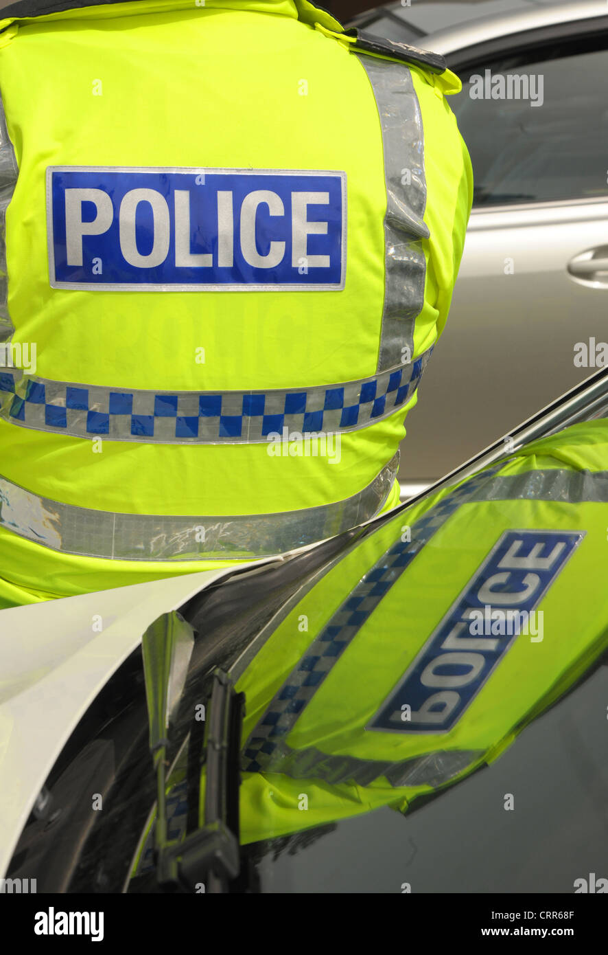 A police officer's logo reflected in his patrol cars windscreen. Yellow vests with blue police logo. Stock Photo