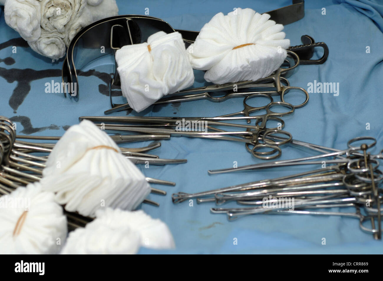 A tray of sterile surgical equipment, including retractors, forceps and swabs. Stock Photo