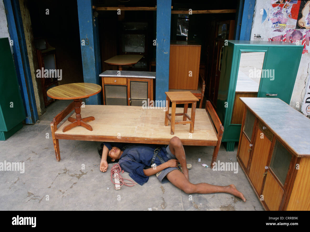A teen working in a shop as a porter is sleeping on the ground ( Nepal) Stock Photo