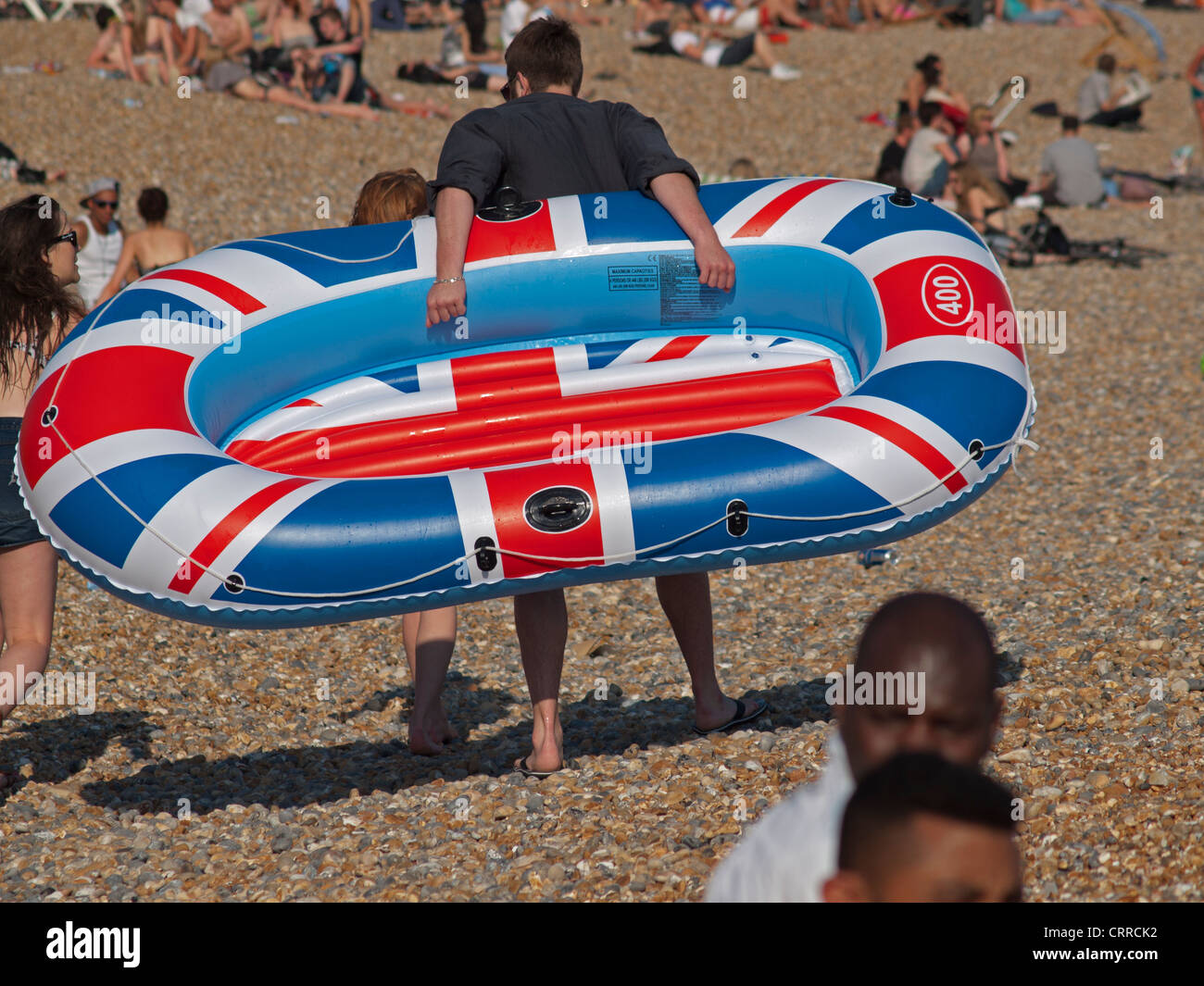 An inflatable boat is carried across Brighton beach. Stock Photo