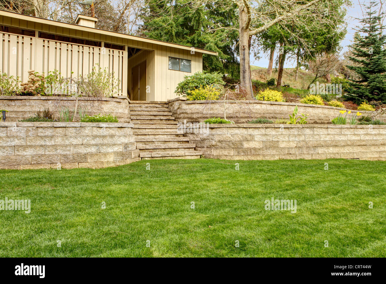 Retaining brick wall with garage building and spring landscape. Stock Photo