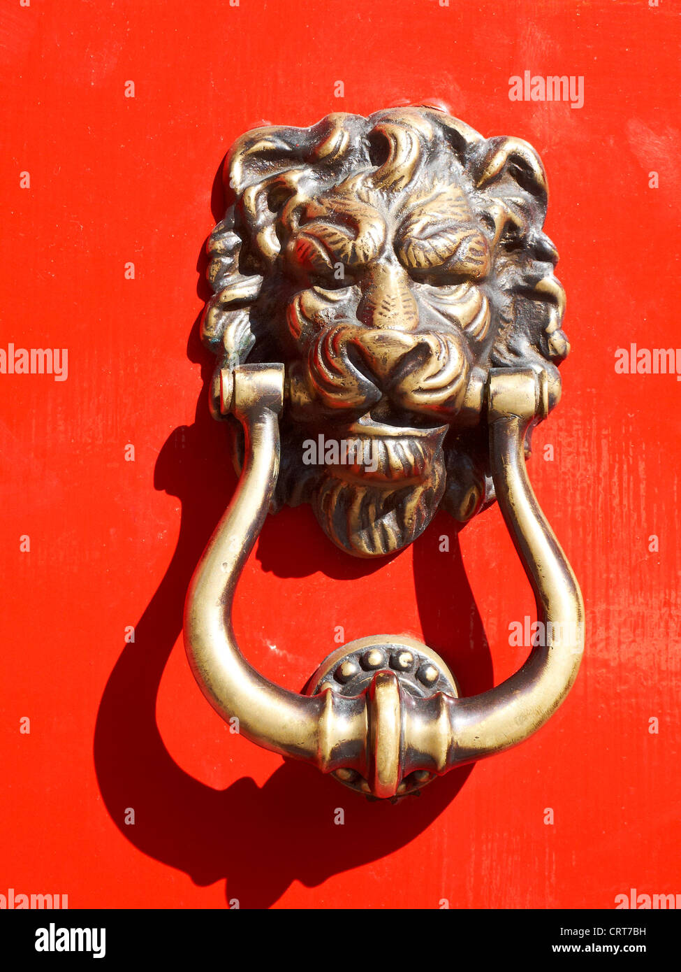 Lion head door knocker on red door Stock Photo