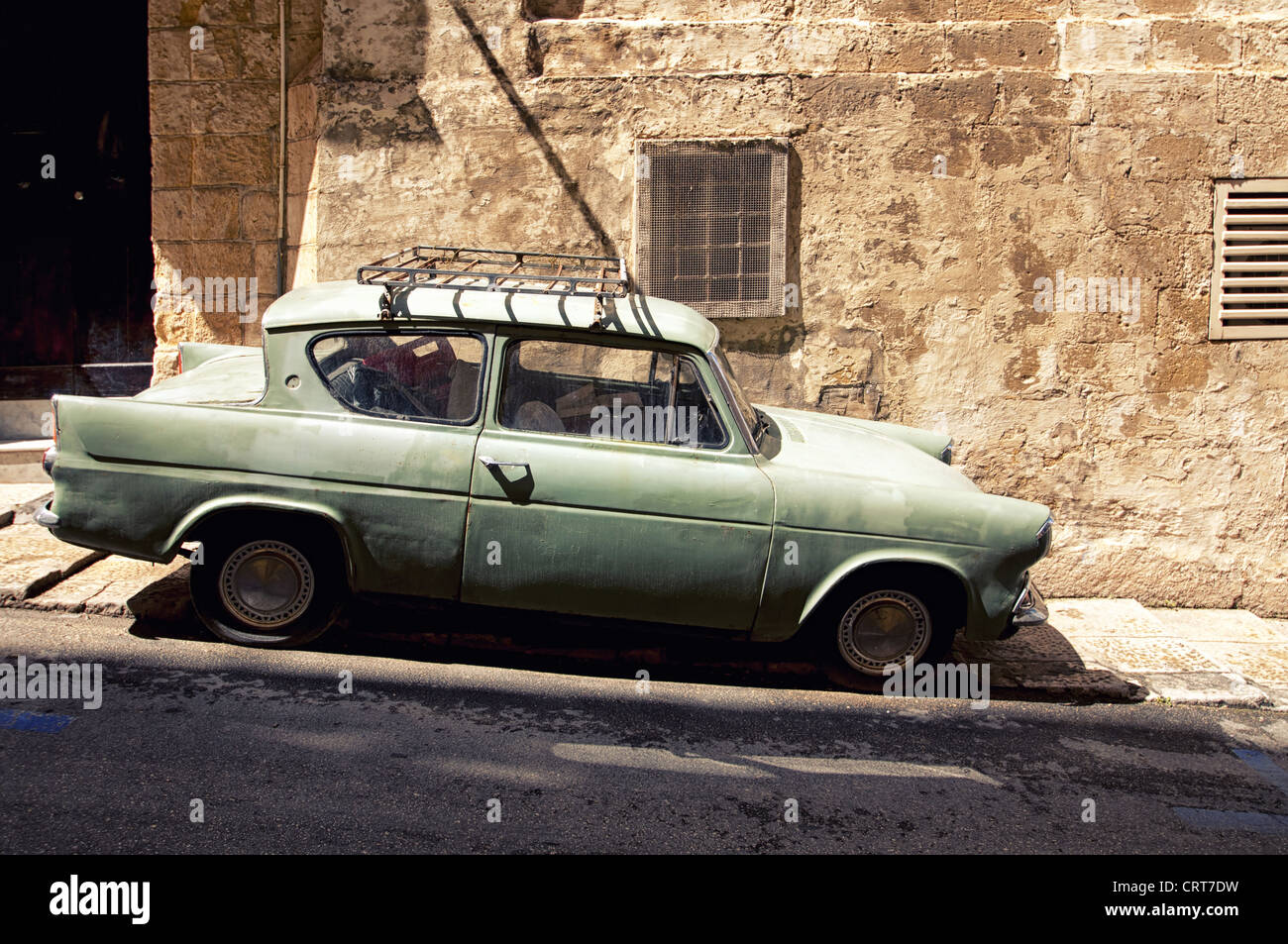 A very old car is parked in a narrow street of Valletta, the capital city of Malta Stock Photo