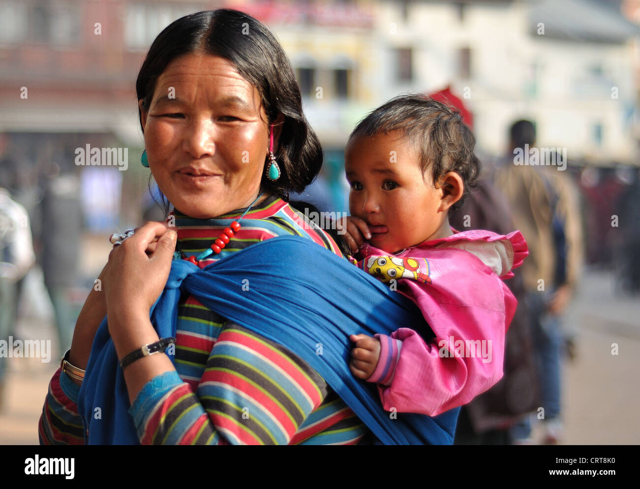 Nepali Mother wearing traditional dress carries her little girl at the