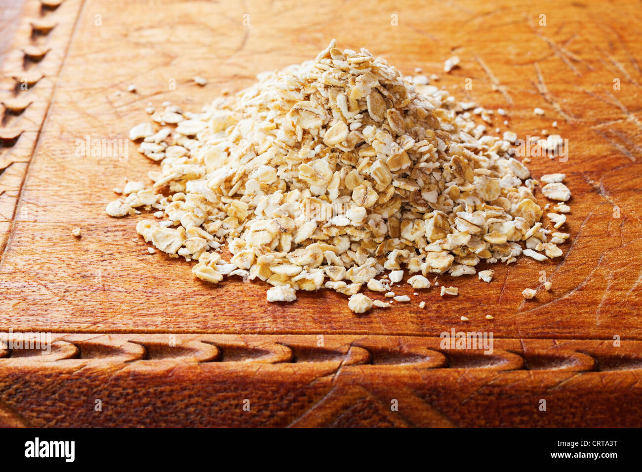 A heap pf raw rolled oats on an old wooden board. Stock Photo