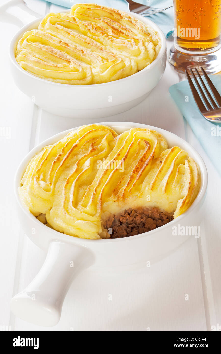 Shepherds Pie or Cottage Pie with a glass of lager in a light bright setting. Stock Photo