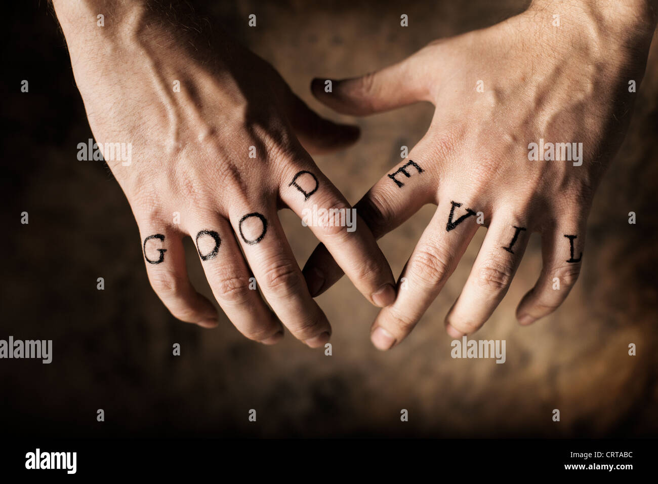 Man with Good and Evil (fake) tattoos on his hands. Stock Photo