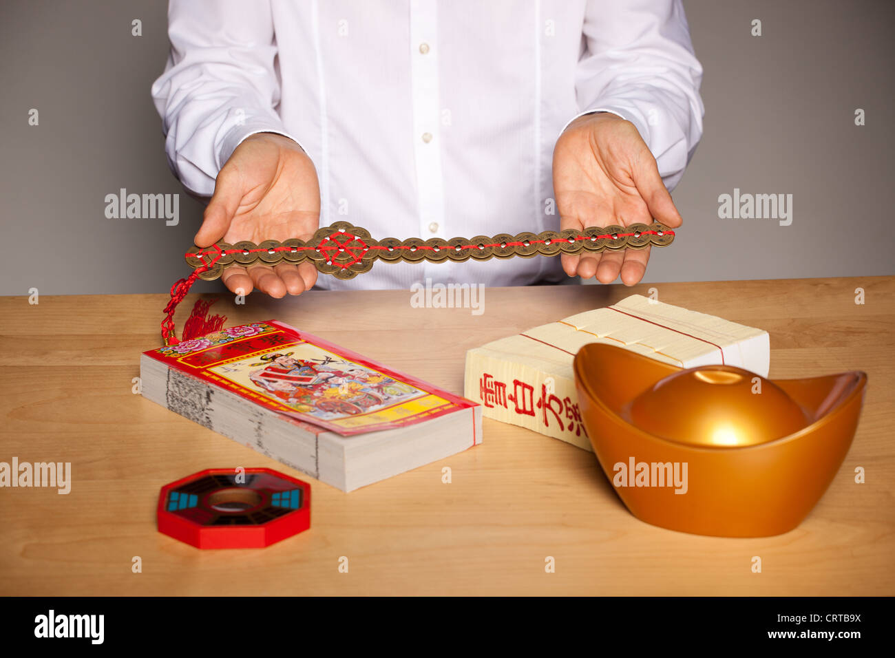 Man's hands with Chinese feng shui accessories on table, holding a