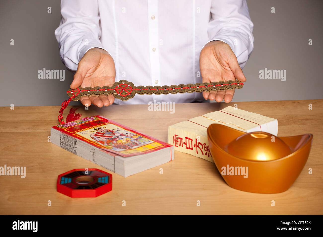Man's hands with Chinese feng shui accessories on table, holding a sword  made up of coins Stock Photo - Alamy