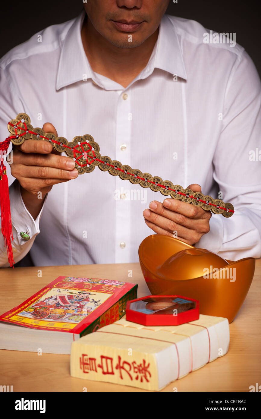 Man's hands with Chinese feng shui accessories on table, holding a