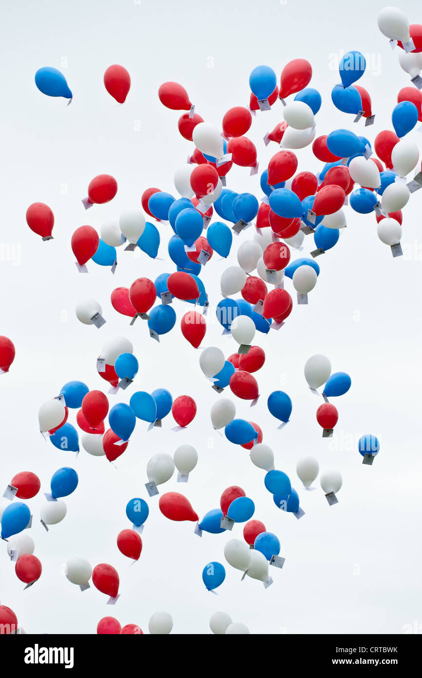 Red, white and blue coloured balloons against a white sky Stock Photo