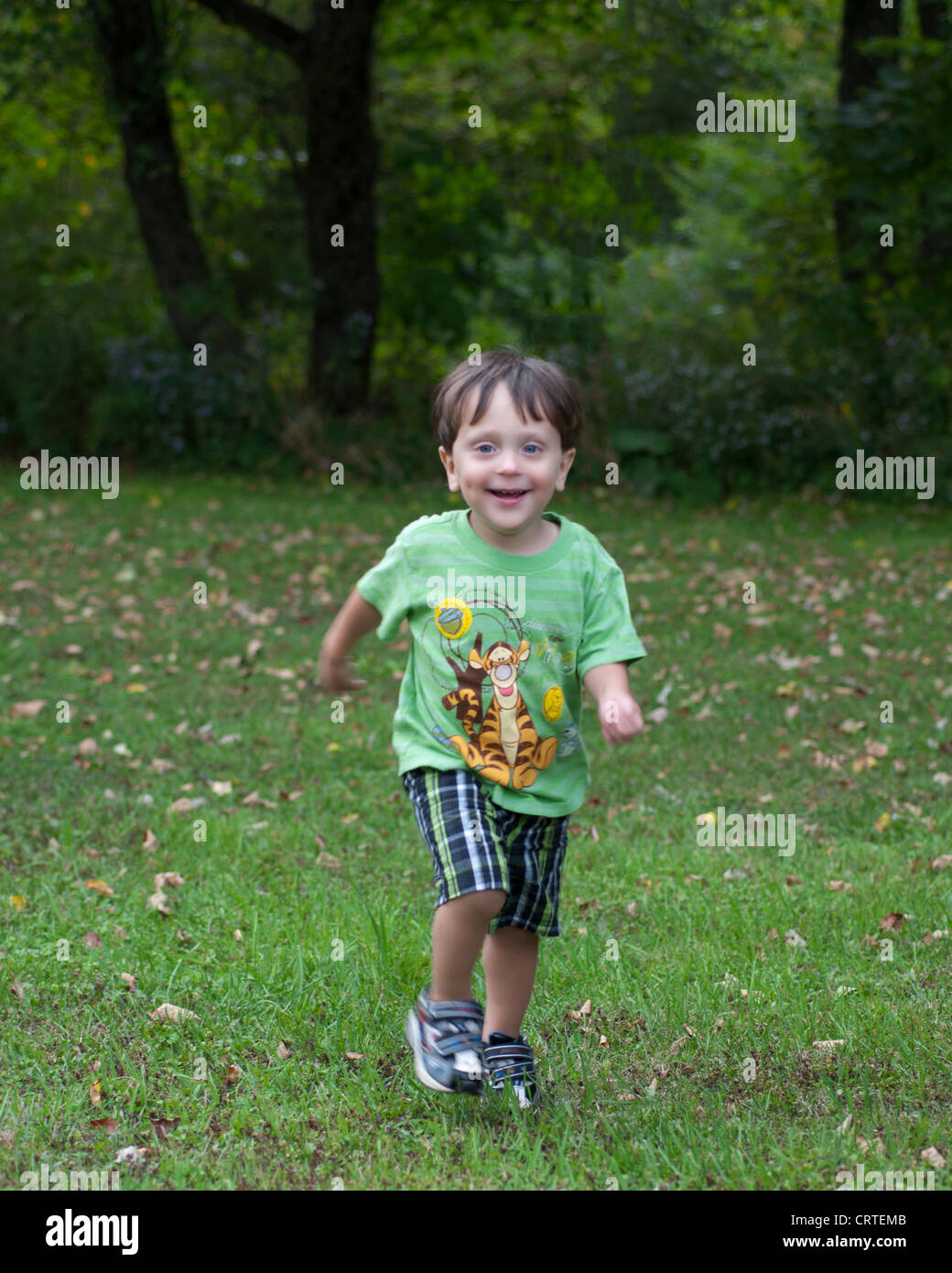 a toddler boy running smiling playing having fun in summer Stock Photo