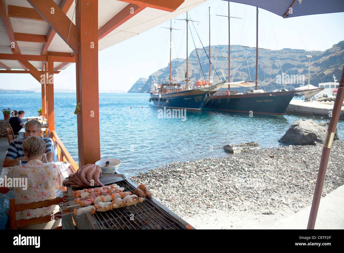 Grilled octopus and prawn skewers on the barbecue in Santorini Greece cooking near the sea caldera cyclades Stock Photo