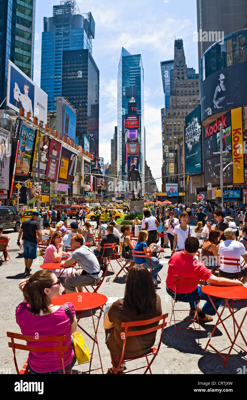 Tourists sitting outside in Times Square, New York City during daytime. Stock Photo