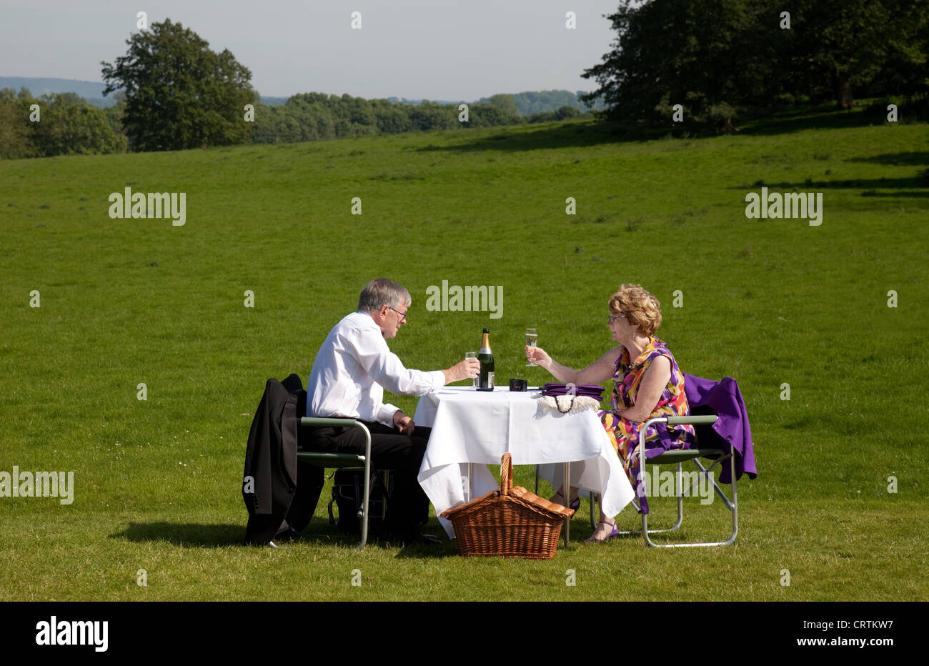 Retired couple enjoying a champagne picnic on the lawn, Glyndebourne opera Festival, Lewes Sussex UK Stock Photo