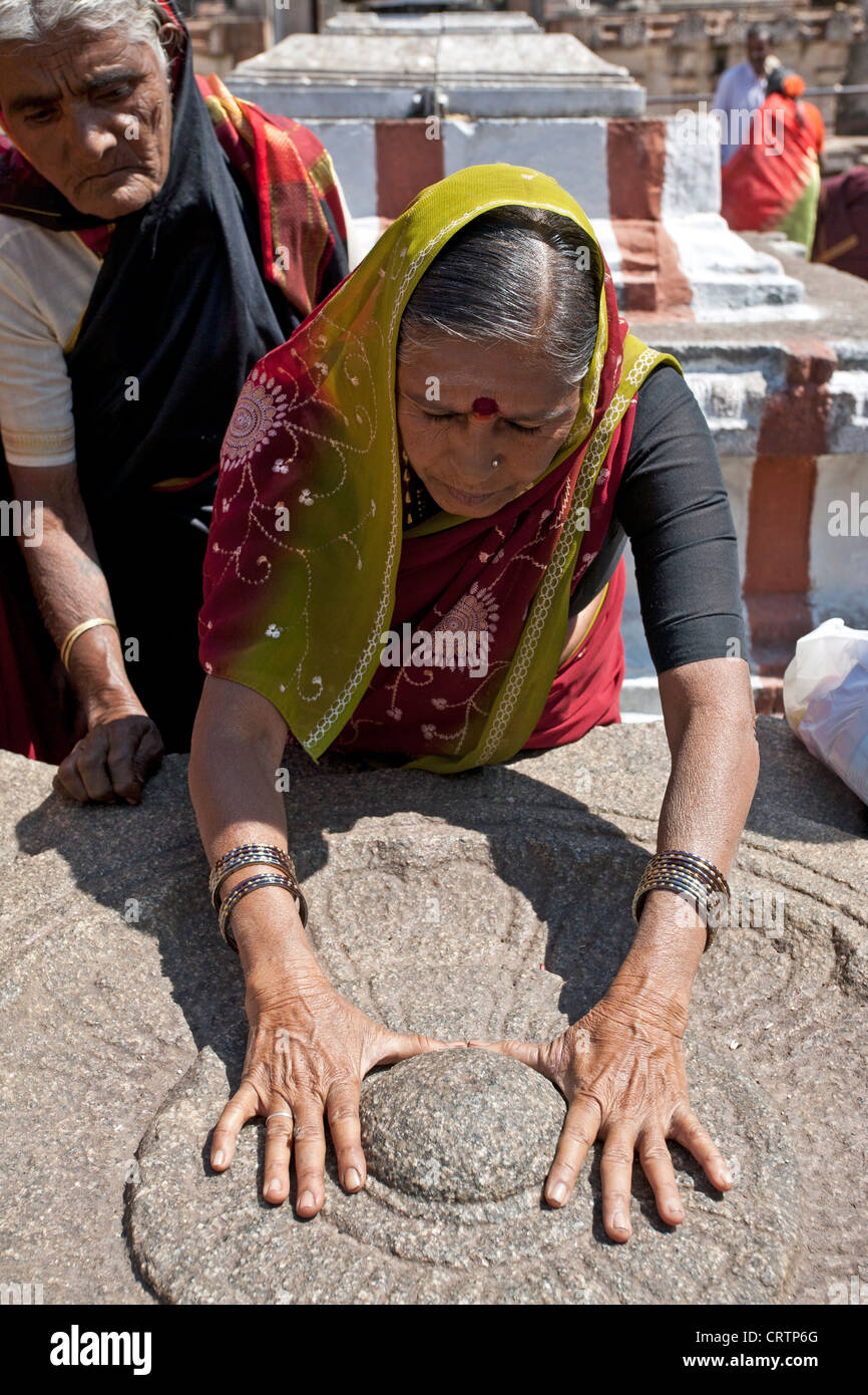 Indian woman worshiping a sacred stone (hindu ritual). Virupaksha temple. Hampi. India Stock Photo