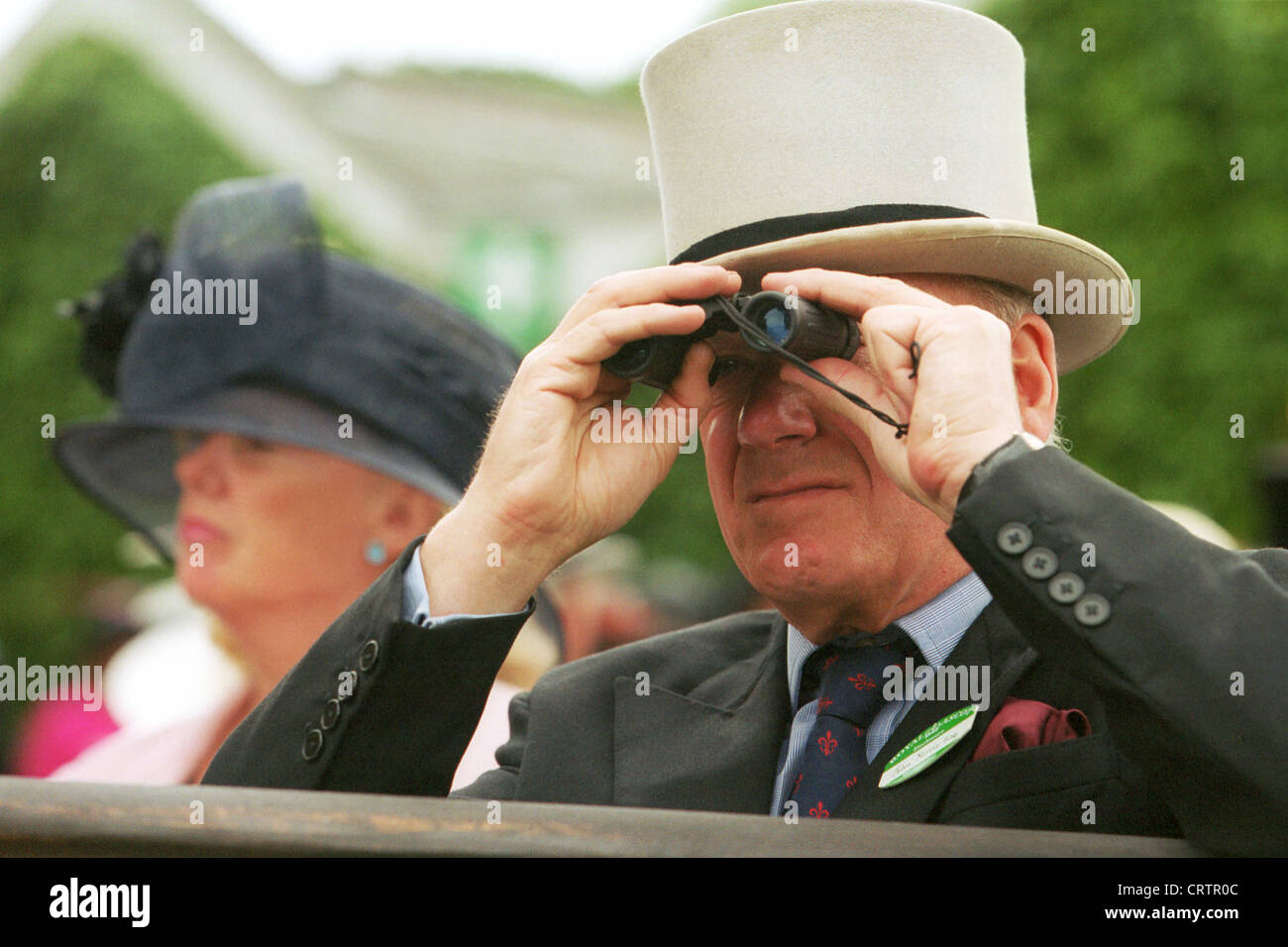 Spectators with binoculars and cylinder on the racecourse Stock Photo