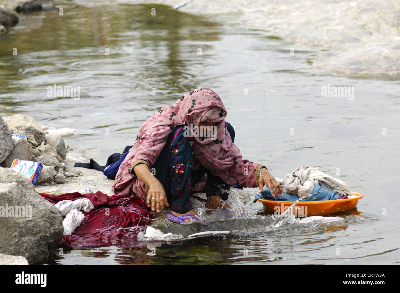 Woman doing her laundry in a river, Oman Stock Photo