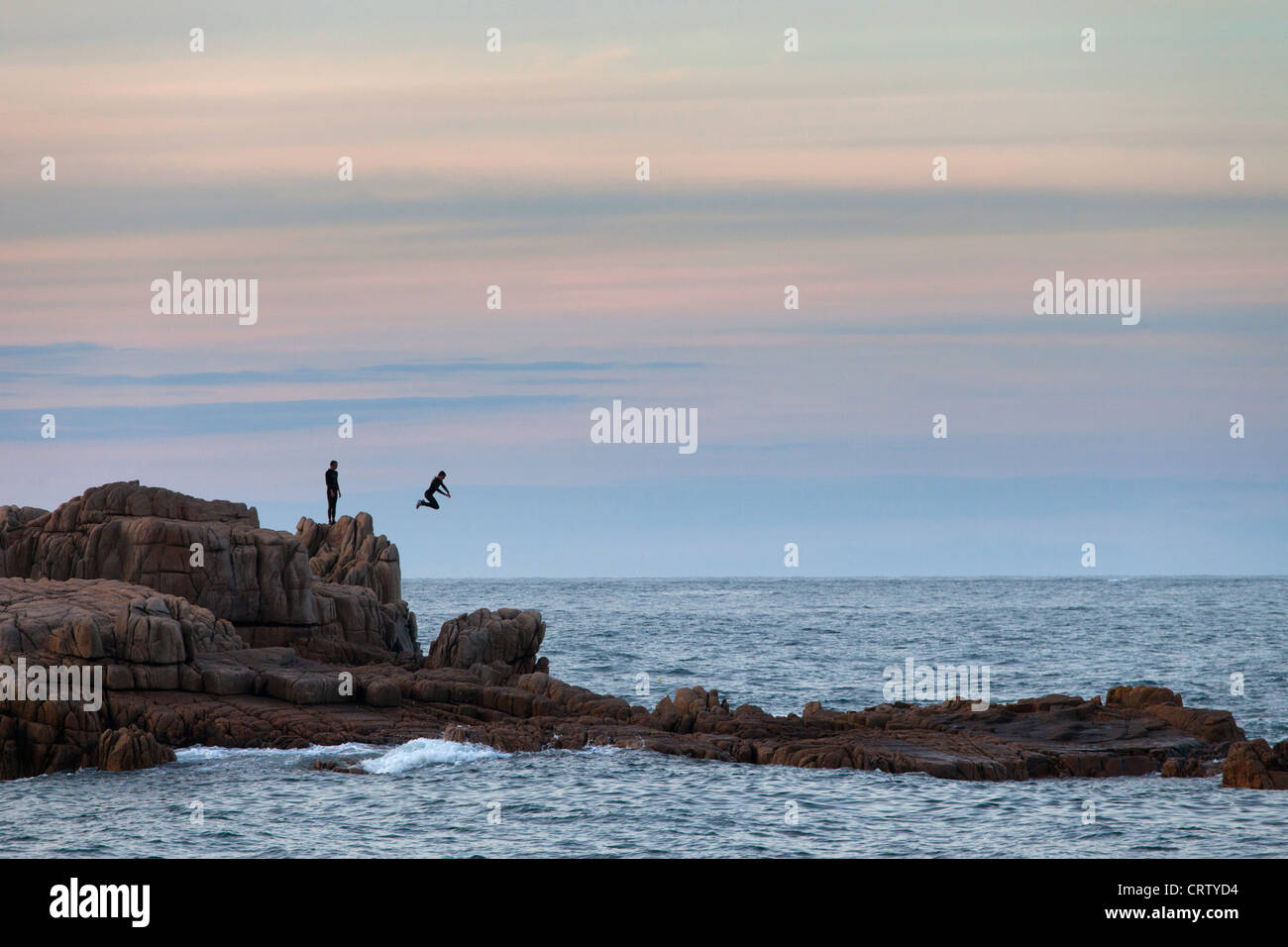 Teenagers jumping off the rocks in Guernsey, Channel Isles, UK Stock Photo
